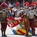 A new recruit of Vatican's elite Swiss Guard gestures while holding flag during swearing-in ceremony at the Vatican